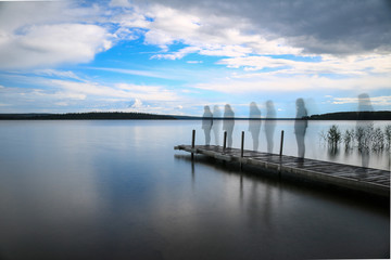 Obraz premium Silhouette of a woman walking on a pier at the lake