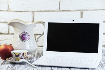 white laptop on a wooden and brick background