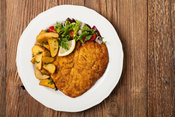 Chicken schnitzel, served with roasted potatoes and salad.