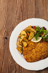 Chicken schnitzel, served with roasted potatoes and salad.