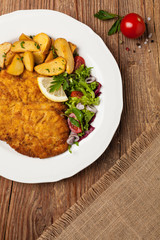 Chicken schnitzel, served with roasted potatoes and salad.
