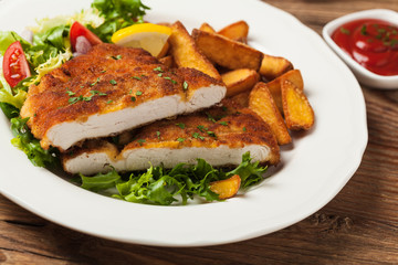 Chicken schnitzel, served with roasted potatoes and salad.