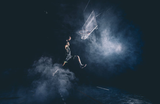 Man jumps playing basket in stadium indor.