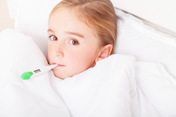 Flu. Young girl lying in bed with a thermometer