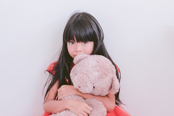 A cute asian kid girl wearing red Chinese dress and holding a teddy bear 