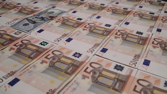 Rows of 50 euro banknotes with a 100 dollar banknote in the middle.