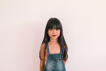 A cute asian kid wearing dungaree and smiling