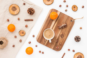 Cup of coffee, pine cone, tangerine, christmas decoration, nuts, wood slice on white background, flat lay, top view