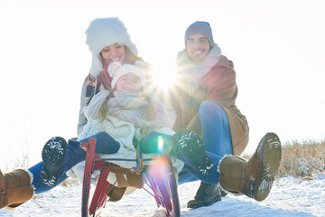 Familie beim Schlitten fahren und rodeln im Winter