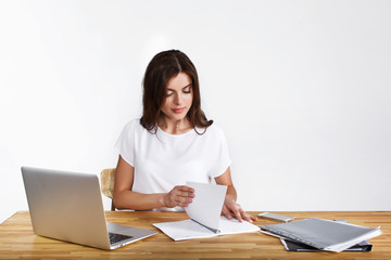 Pretty woman works with a laptop and notebook at the table