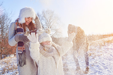 Familie beim Spielen im Winter im Schnee - obrazy, fototapety, plakaty