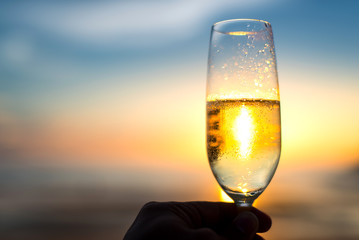 Glass of champagne at sunset dramatic sky background.