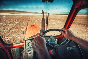 Obraz premium Closeup hands of farmer, sits inside in the tractor cabin