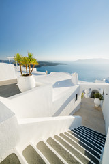 White walls and pot plants along a walkway in Santorini, Greece.White walls and pot plants along a...