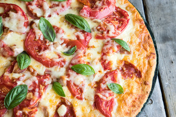 Hot Homemade Pepperoni Pizza on a rustic wooden table. Pizza with tomato, cheese and basil with copy space