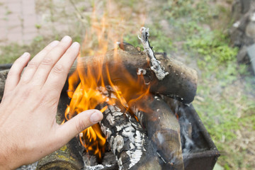 man warming his hand by a fire. Poor men warm outdoors near smoking barrel