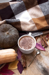 Rural wooden background with pumpkin and autumn leaves, a cup of pumpkin latte with coffee or cocoa, a notebook, a plaid in a cage, top view. Autumn background.