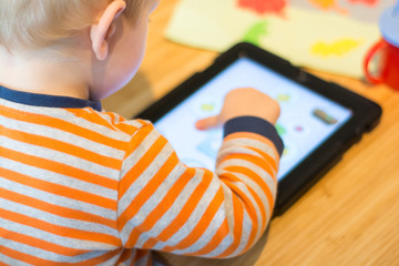 Child using a touch screen tablet to play learning game