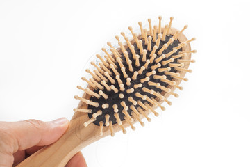 hand holding Wooden hairbrush with hair fallen isolated on white background
