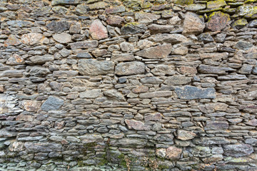 Side view of the grey stone patterns on an old dry stone wall.
