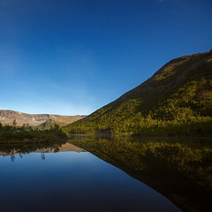 Fototapeta premium Mountains reflected in the smooth surface of the lake at dawn.