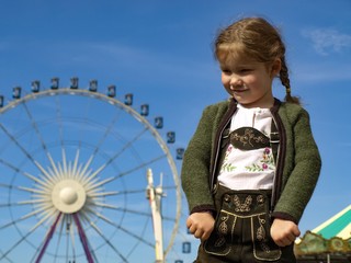 M&auml;dchen in Lederhose vor Riesenrad auf Rummelplatz