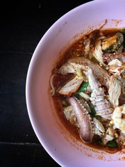 Noodles seefood Tom yum with squid and mantis shrimp, squid, prawn in a bowl on wooden table, still life and Thai style food.
