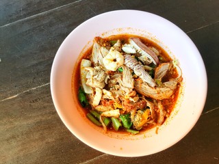Noodles seefood Tom yum with squid and mantis shrimp, squid, prawn in a bowl on wooden table, still life and Thai style food.