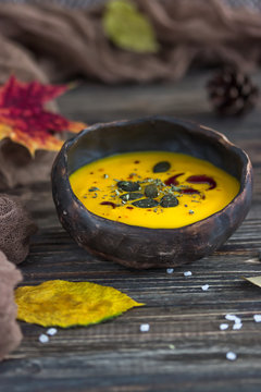 Vegetarian pumpkin cream soup with pumpkin seeds and pumpkin oil on a dark background. Rustic style