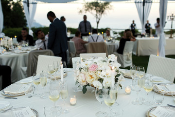 Glasses with white wine and champagne stand around white bouquet on dinner table