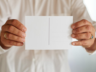 Frau mit weißer Bluse hält weiße leere Karte