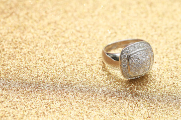 Fototapeta na wymiar diamond ring on gold glitter background