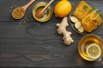 healthy background. honey, honeycomb, lemon, tea, ginger on dark wooden table. Top view with copy space
