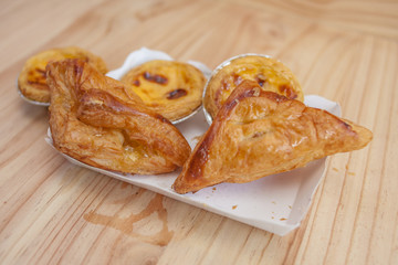 Egg tart or portuguese egg tart  and sugar palm pie on recycled paper. On the wood floor.