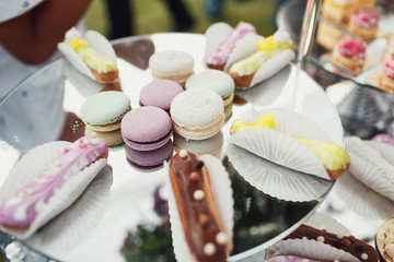 Eclairs with colorful icing served on a white dish with macaroons