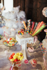 Fototapeta premium Glass bowls with colorful chocolate pills stand on wedding candy bar