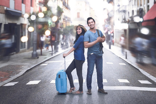 Happy asian couple with baggage enjoying vacations