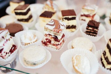 Delicious chocolate cookies and cakes, white macaroons on a glass table