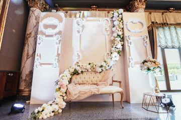 Place for photos made of cosy sofa and flower garlend hanging over it