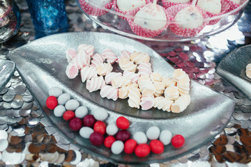 Silver leaf with marshmallow and chocolates stands on the table