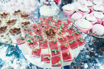 Cups with cold desserts with strawberry stand on plate on silver table