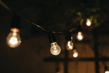 Illuminated light bulbs hanging outdoors at night
