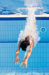 Young woman dives into the swimming pool © Microgen