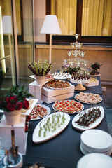 Black dinner table served with white dishes with snacks