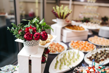 Dinner table with snacks decorated with red peonies