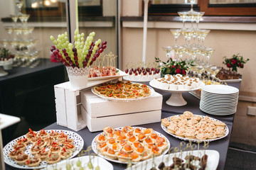 Black dinner table served with white dishes with snacks