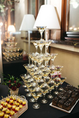 Pyramid made of cocktail glasses stands on black table