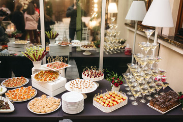 Black dinner table served with white dishes with snacks