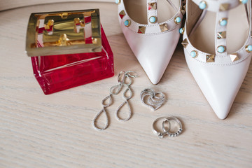 Silver earrings, rings and pendant lie before the shoes