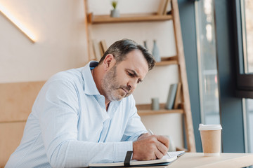 Naklejka premium businessman writing in notebook